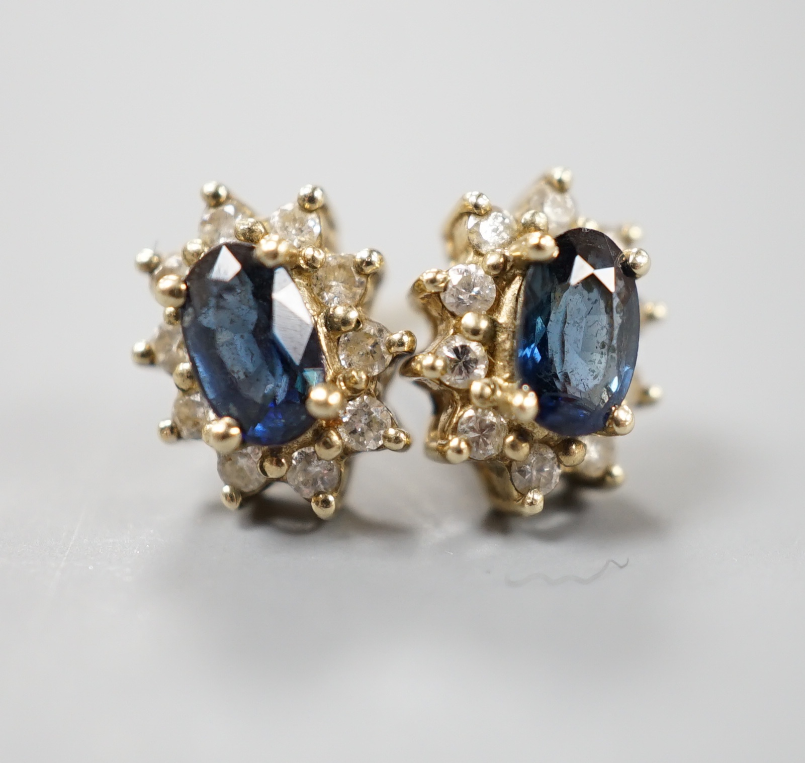 A pair of modern 9ct gold, sapphire and diamond chip set oval cluster earrings, gross 1.3 grams.